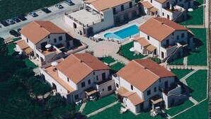 An aerial view of a residential area with multiple houses, a swimming pool, and a parking lot. - Borgo Valmarina (Follonica)