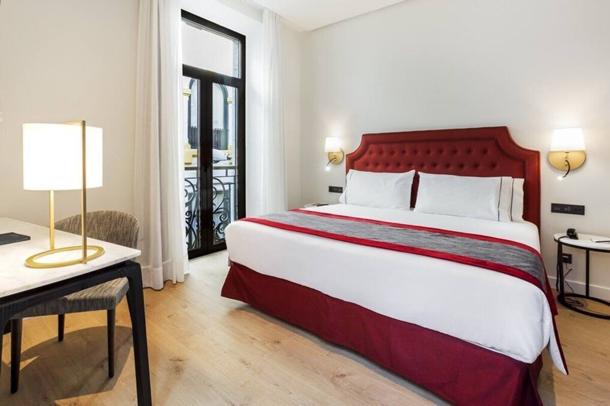 Een hotelkamer met een bed, een bureau, een stoel en uitzicht.