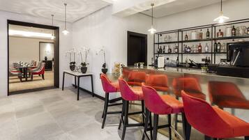 A modern kitchen with a bar area, red bar stools, and a wine rack with various bottles.