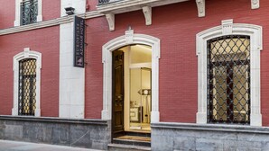 L’entrée d’un hôtel, avec une façade en briques rouges, des éléments décoratifs blancs et une enseigne indiquant « Eurostars Azahar Hotel ».