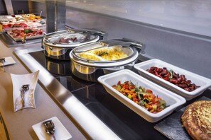 Un buffet proposant une variété de plats, notamment des viandes, des légumes et une sorte de pain plat.
