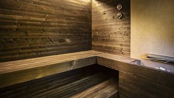 Un sauna avec des murs et des bancs en bois, une horloge et un porte-serviettes.