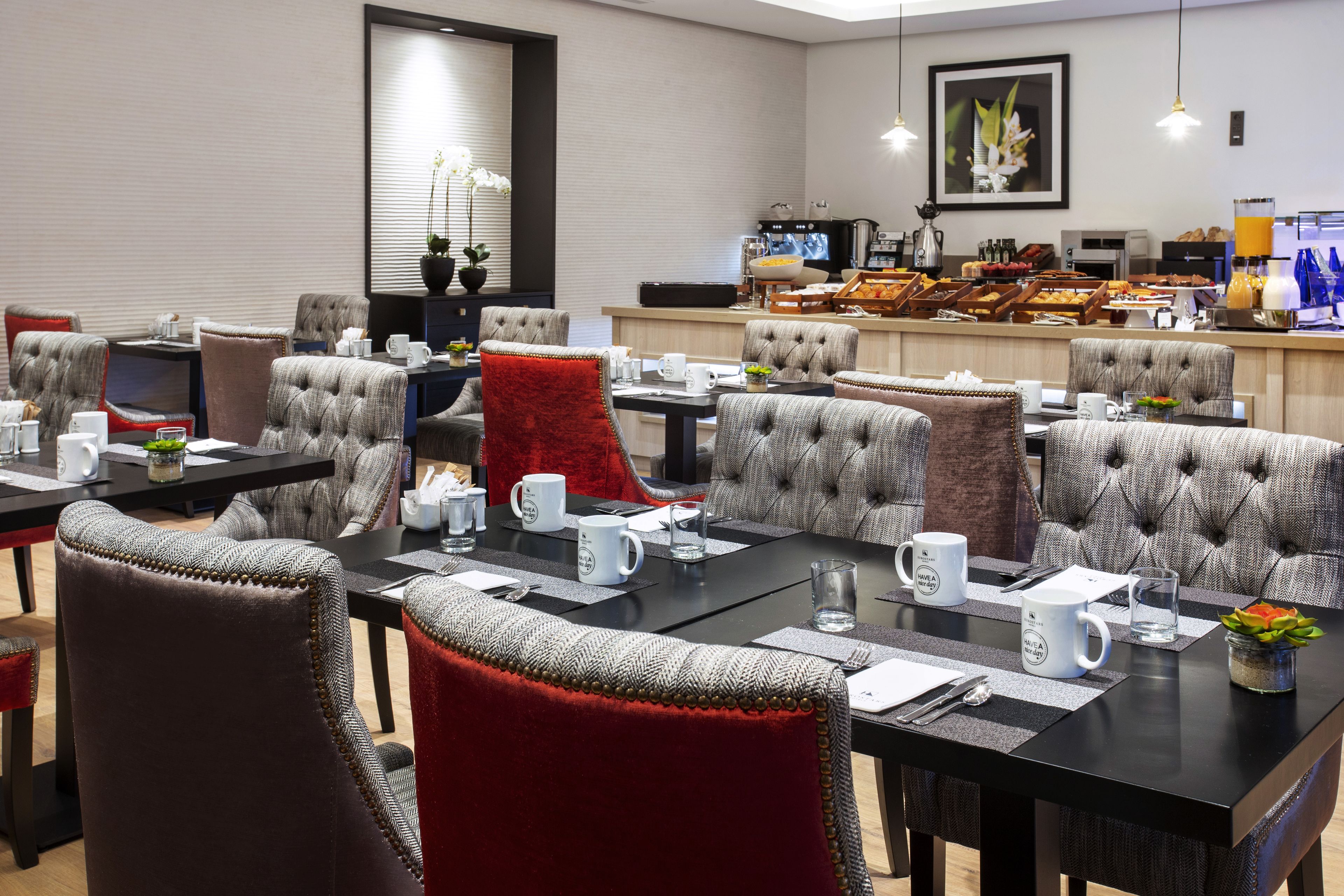 A conference room with multiple tables and chairs, a buffet area with various food items, and a television screen.