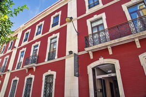 Un edificio rojo con detalles blancos, un letrero que indica Hotel Eurostars Azaklar, y un balcón con barandillas de metal ornamentado.