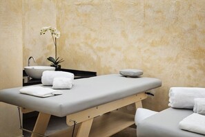 Une salle de soins équipée d’une table de massage, d’un lavabo et d’une petite plante.