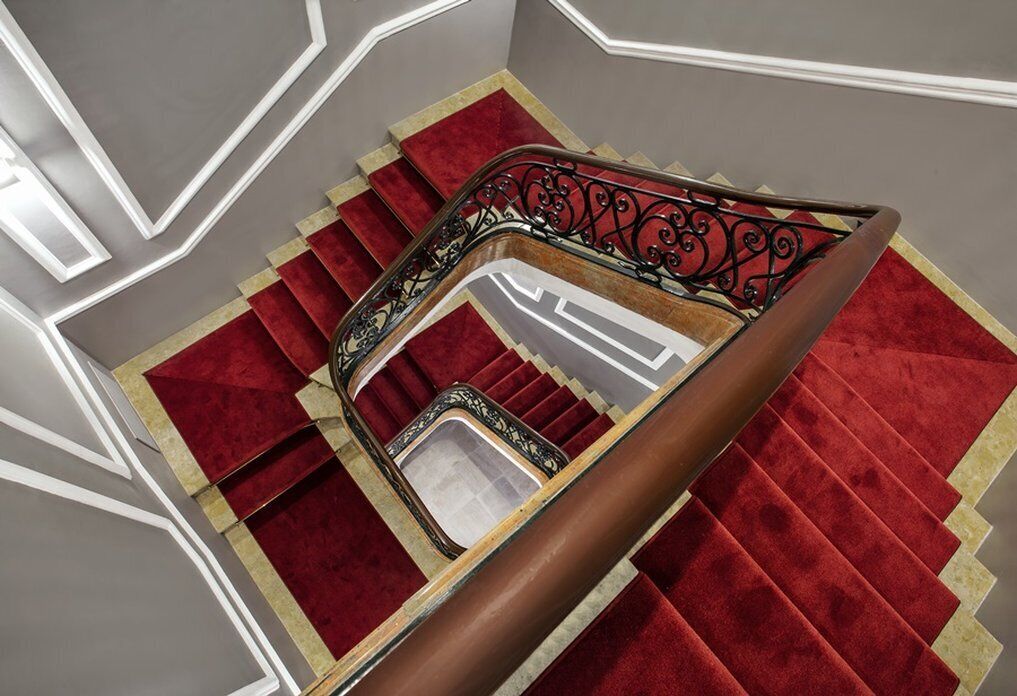 A staircase with a red carpet and a metal railing.