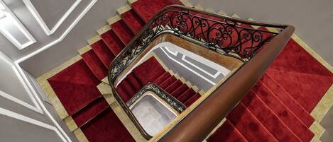 A staircase with a red carpet and a metal railing.