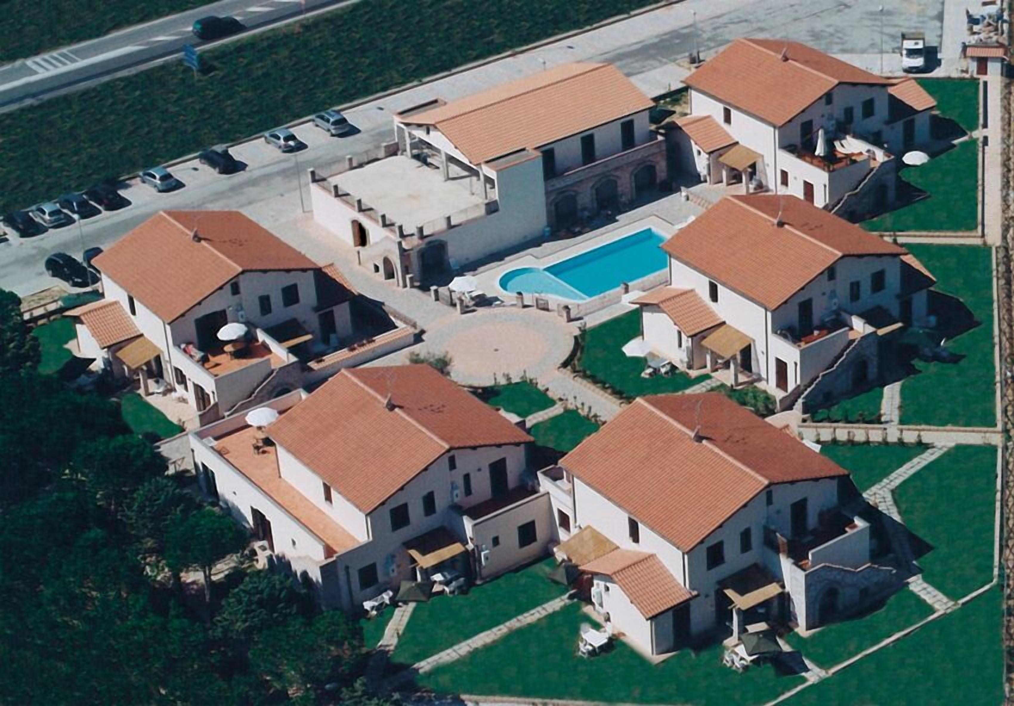 An aerial view of a residential area with multiple houses, a swimming pool, and a parking lot.