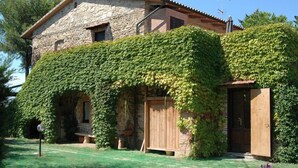 A stone house with a wooden door and a window, partially covered by ivy. - Podere Valmarina (Grosseto)