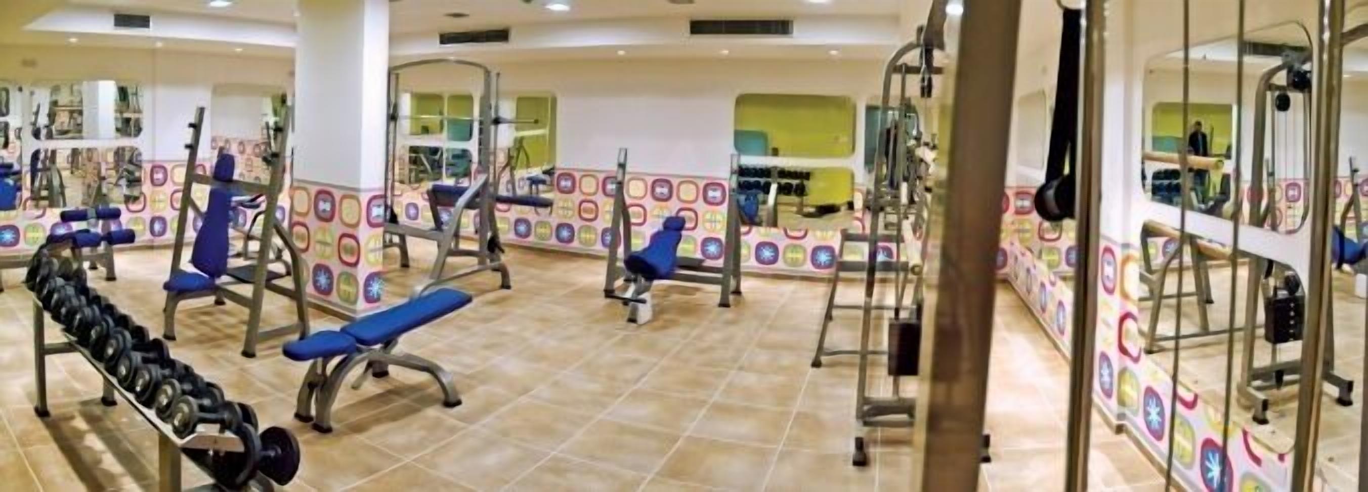 A gym with various exercise equipment, including benches, dumbbells, and weight machines.