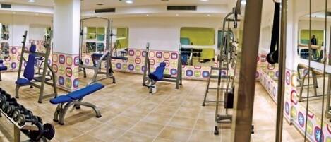 A gym with various exercise equipment, including benches, dumbbells, and weight machines.