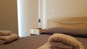 A neatly made bed with a brown bedspread and two pillows, a bedside table with a lamp, and a folded towel on the bed. - Marand Apartment BF11 (Paralimni)