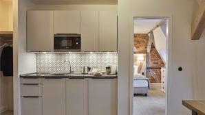 Eine moderne Küche mit weißen Schränken, einer gemusterten Spritzschutzwand und einem Holzboden.