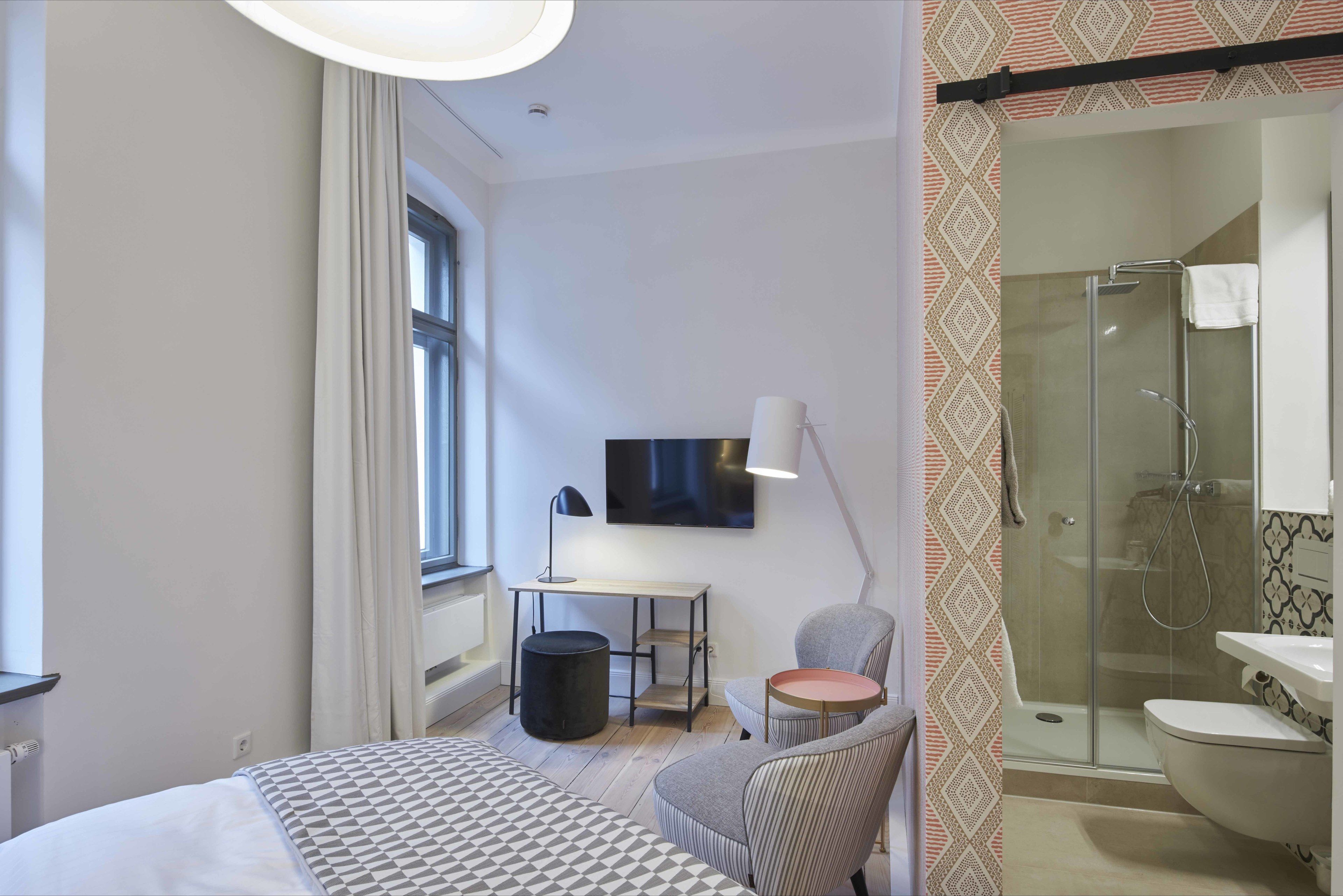 Ein modernes Schlafzimmer mit Bett, Schreibtisch, Stuhl und Fernseher.