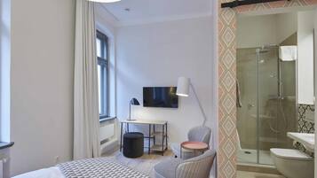 Ein modernes Schlafzimmer mit Bett, Schreibtisch, Stuhl und Fernseher.