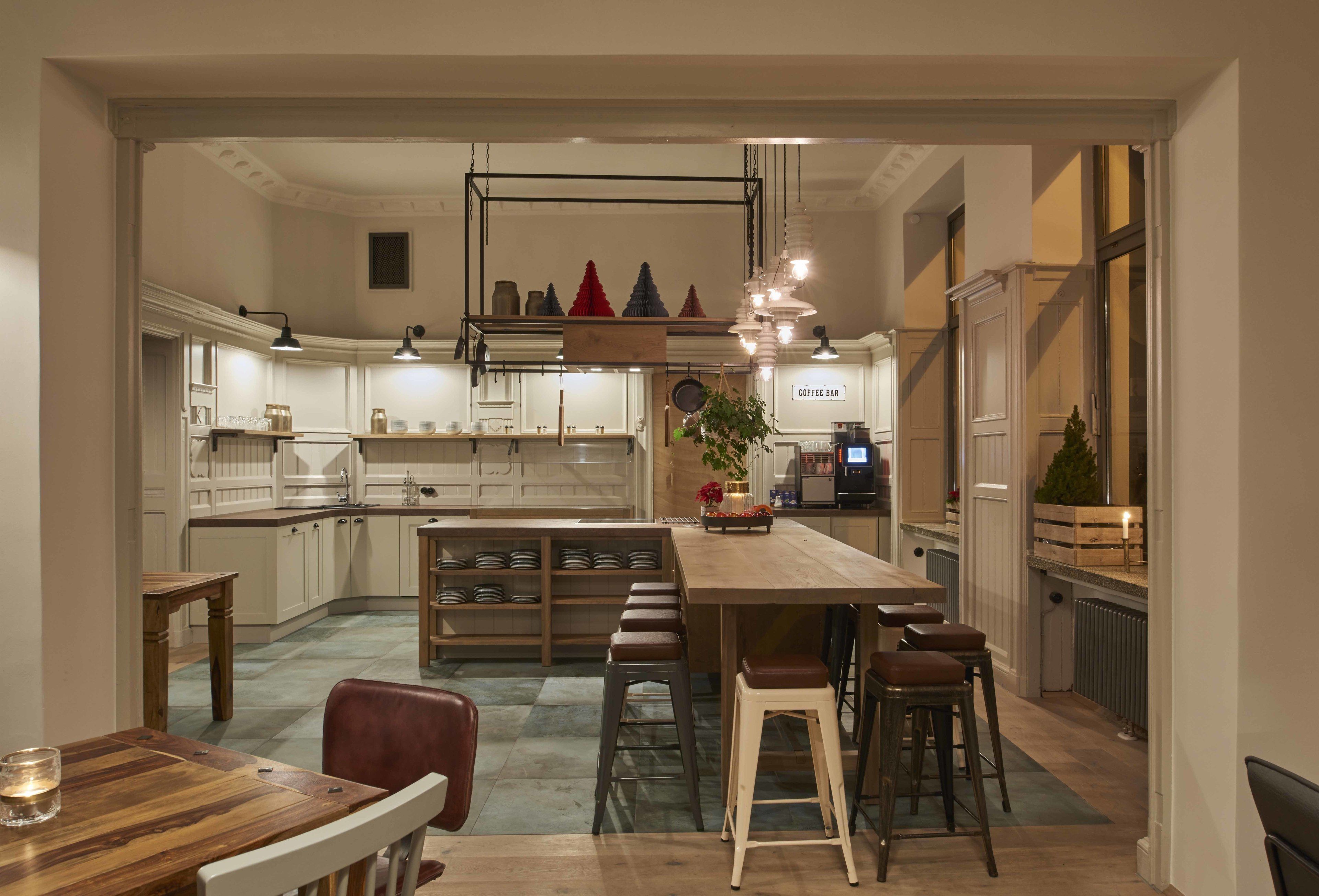 A modern kitchen with a central island, bar stools, and a coffee bar.