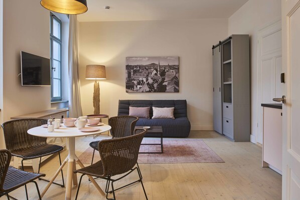 Una sala de estar moderna con sofá, sillones, una mesa de centro y televisión.