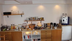 A compact kitchen with wooden cabinets, a coffee machine, and various kitchen utensils. - Villa Wolkenlos (Dahme)