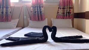 A hotel room with two beds, each with a white mattress and pillows. There are curtains with a circular pattern on the windows. - Hotel Riddhi Siddhi Restaurant & Bar (Birgunj)