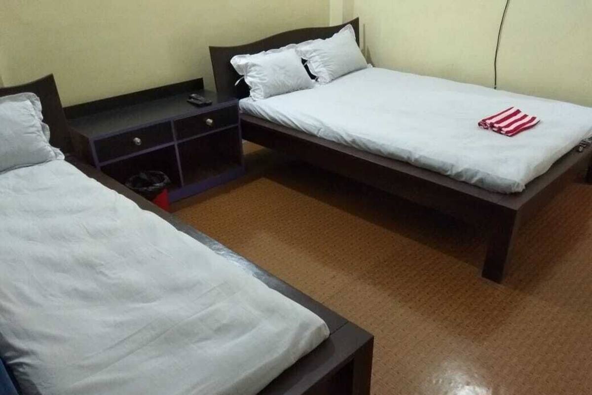 Ein Zimmer mit zwei Einzelbetten, einem kleinen Schreibtisch und einem Stuhl.