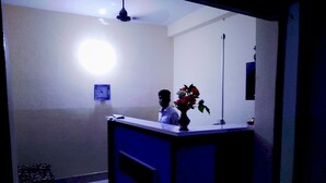 A reception desk with a vase of flowers, a clock on the wall, and a ceiling light. - Hotel Riddhi Siddhi Restaurant & Bar (Birgunj)