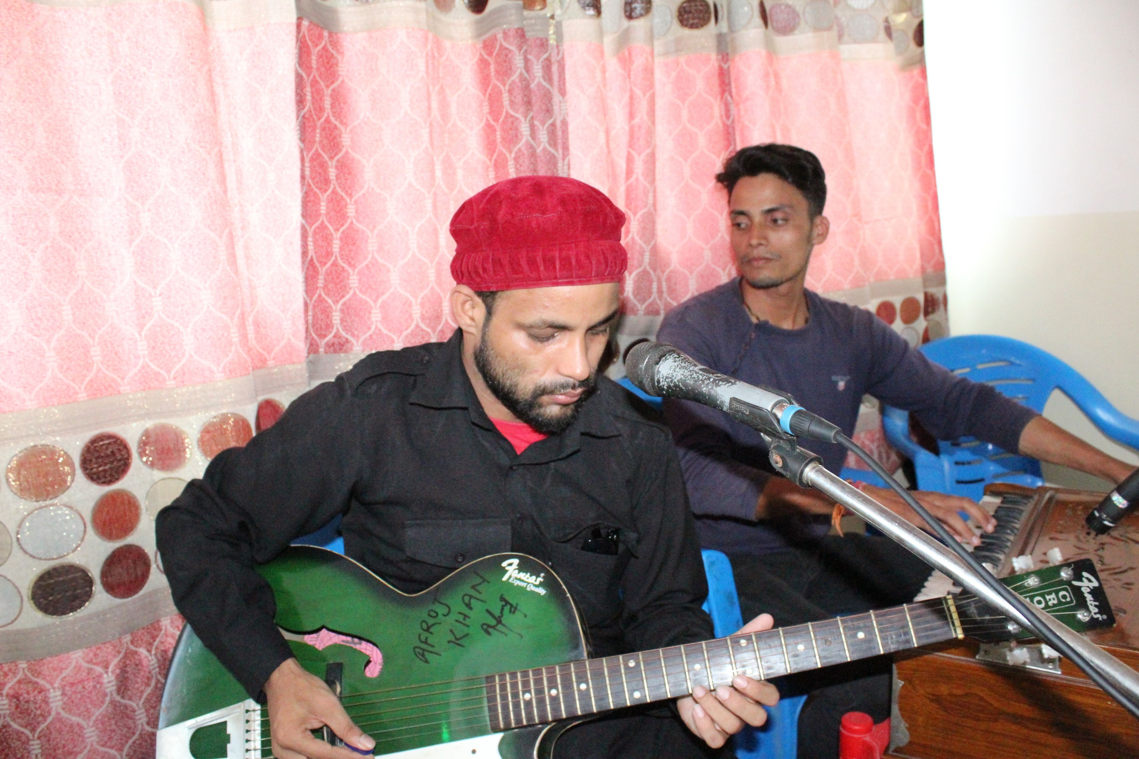 A person playing a guitar with a microphone in front of them.