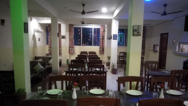A dining area with multiple tables and chairs, ceiling fans, and potted plants. - Hotel Riddhi Siddhi Restaurant & Bar (Birgunj)