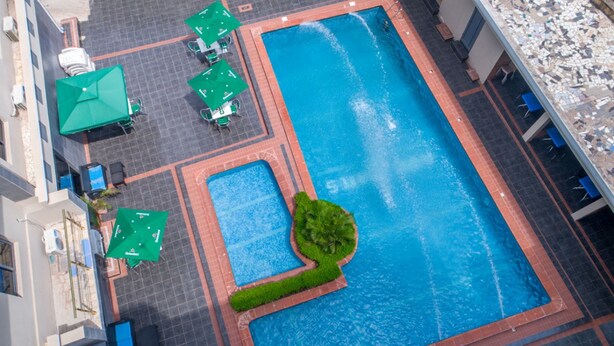 Vista aérea de una piscina con zonas de descanso y vegetación circundante.