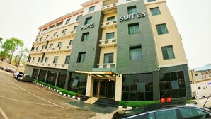 Un hotel de varios pisos con letreros que indican 'ADIG' y 'SUITES', que presenta un diseño moderno con techo plano y grandes ventanales.