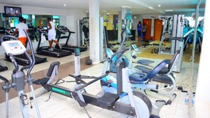 Un gimnasio con cintas de correr, elípticas y equipo de pesas.