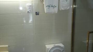 Un baño con inodoro, bidé y cabina de ducha de vidrio.