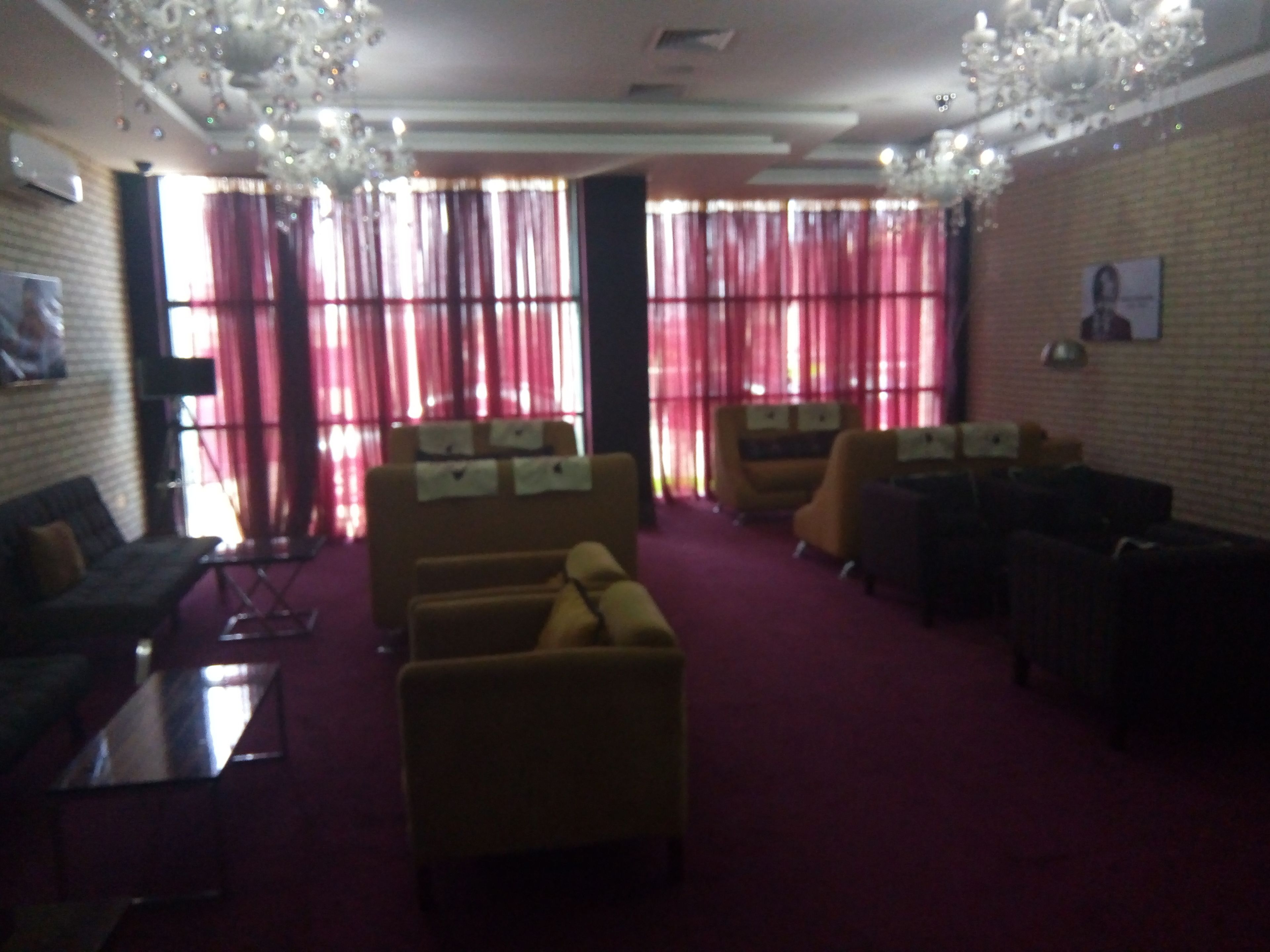 A spacious lobby with a red carpet, multiple seating areas, and a chandelier.
