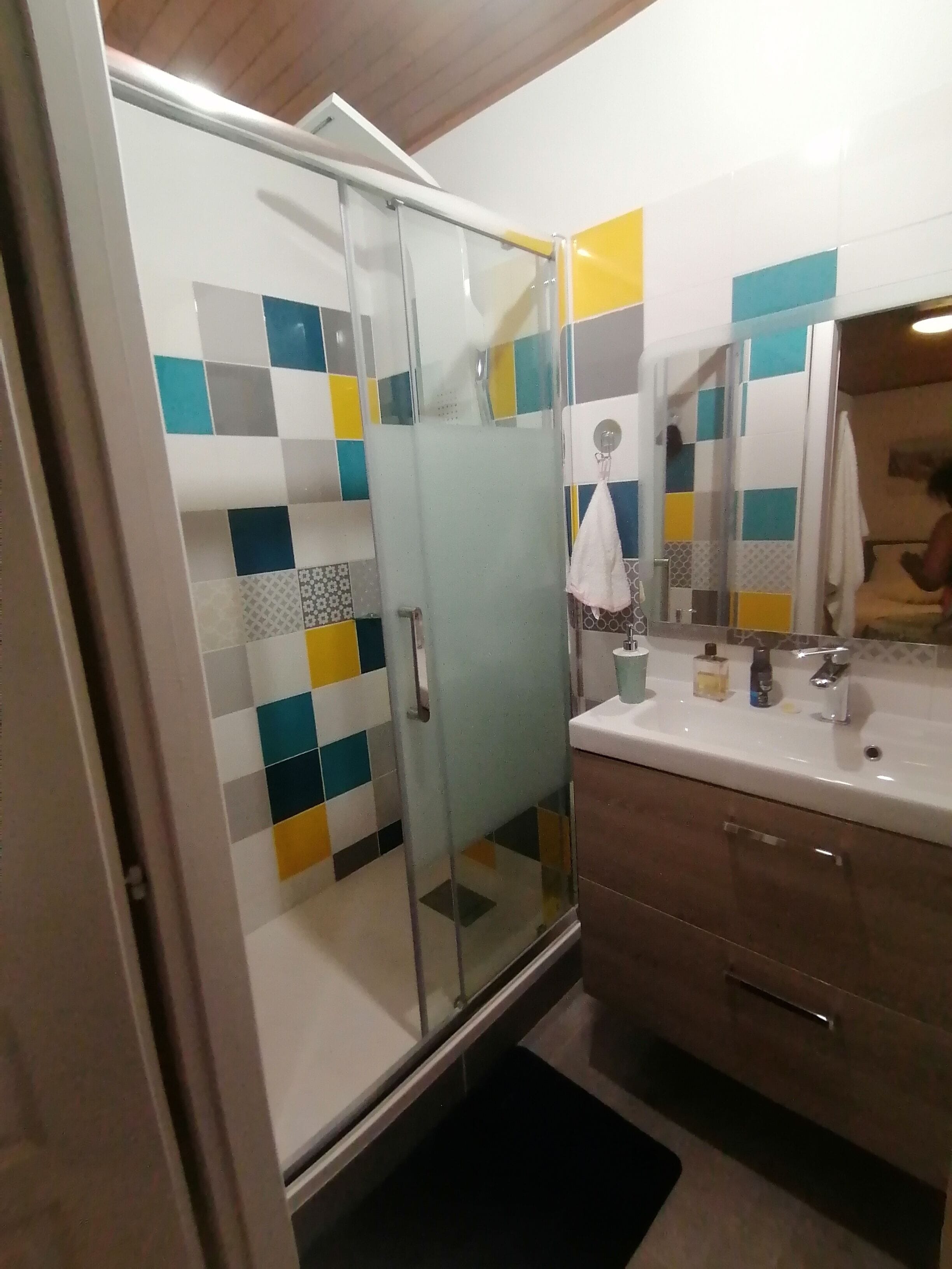 A bathroom with a glass shower enclosure, a white sink, and a mirror.