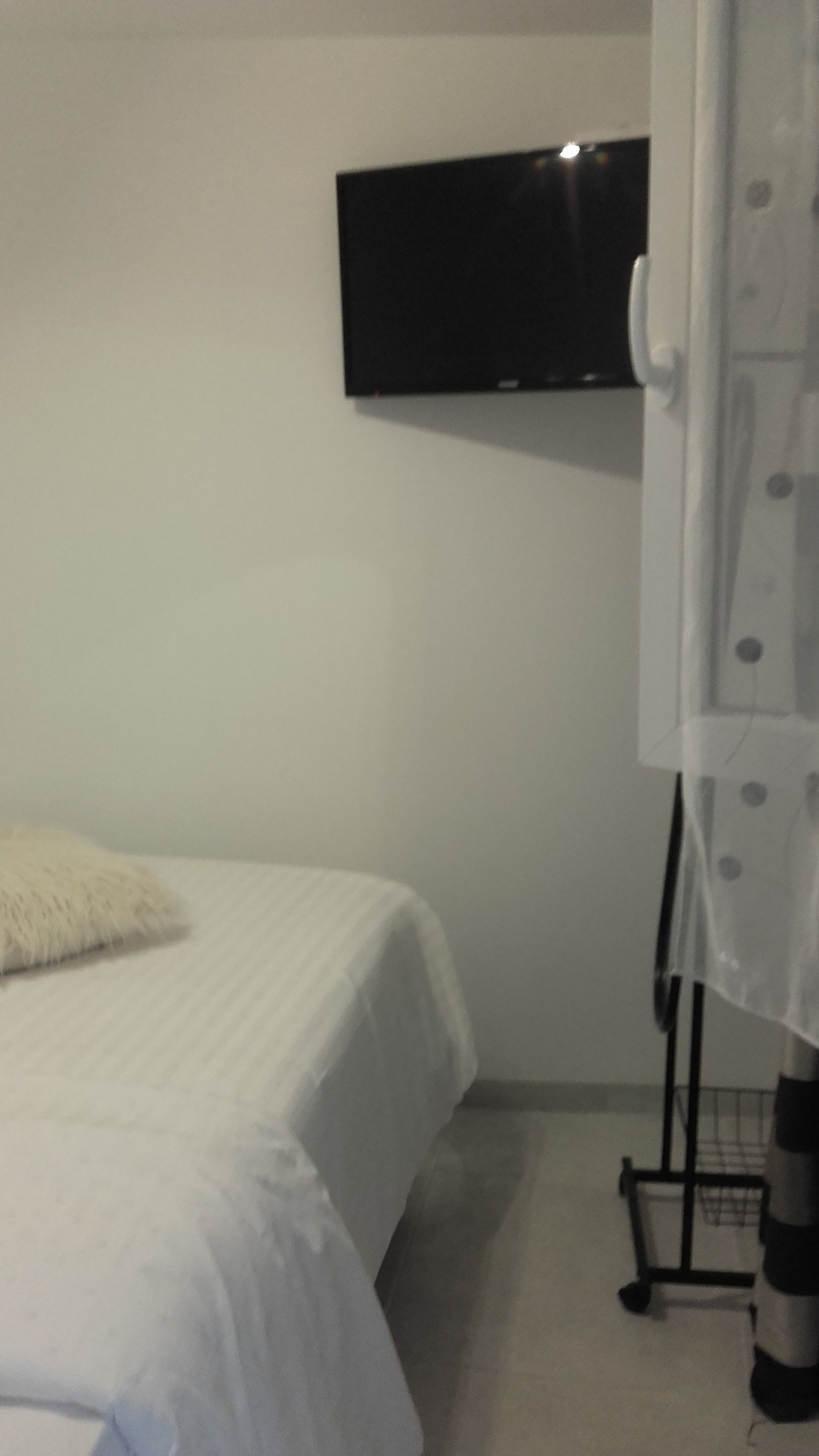 Una camera da letto con un letto, una televisione a parete e un tavolino con un cesto.