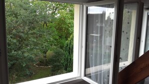 A room with a large window overlooking a garden. - Chambre du Jardin Fleuri (Saint-Aubin-Les-Elbeuf)