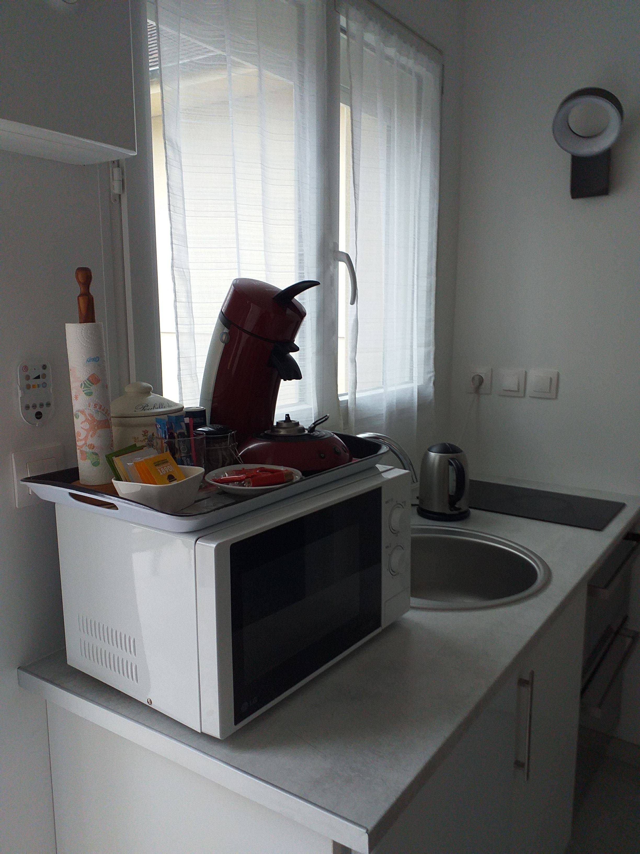 Cucina con forno a microonde, bollitore e finestra con persiane.