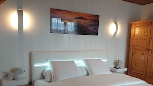 A bedroom with a large bed, a wooden wardrobe, and a painting on the wall. - Chambre du Jardin Fleuri (Saint-Aubin-Les-Elbeuf)