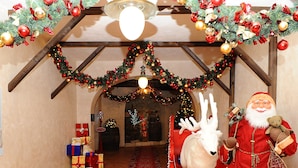 A decorated indoor space with a Christmas theme, including a Santa Claus figure, a reindeer, and a Christmas tree. - Il Villaggio di Giuele (Finale Ligure)
