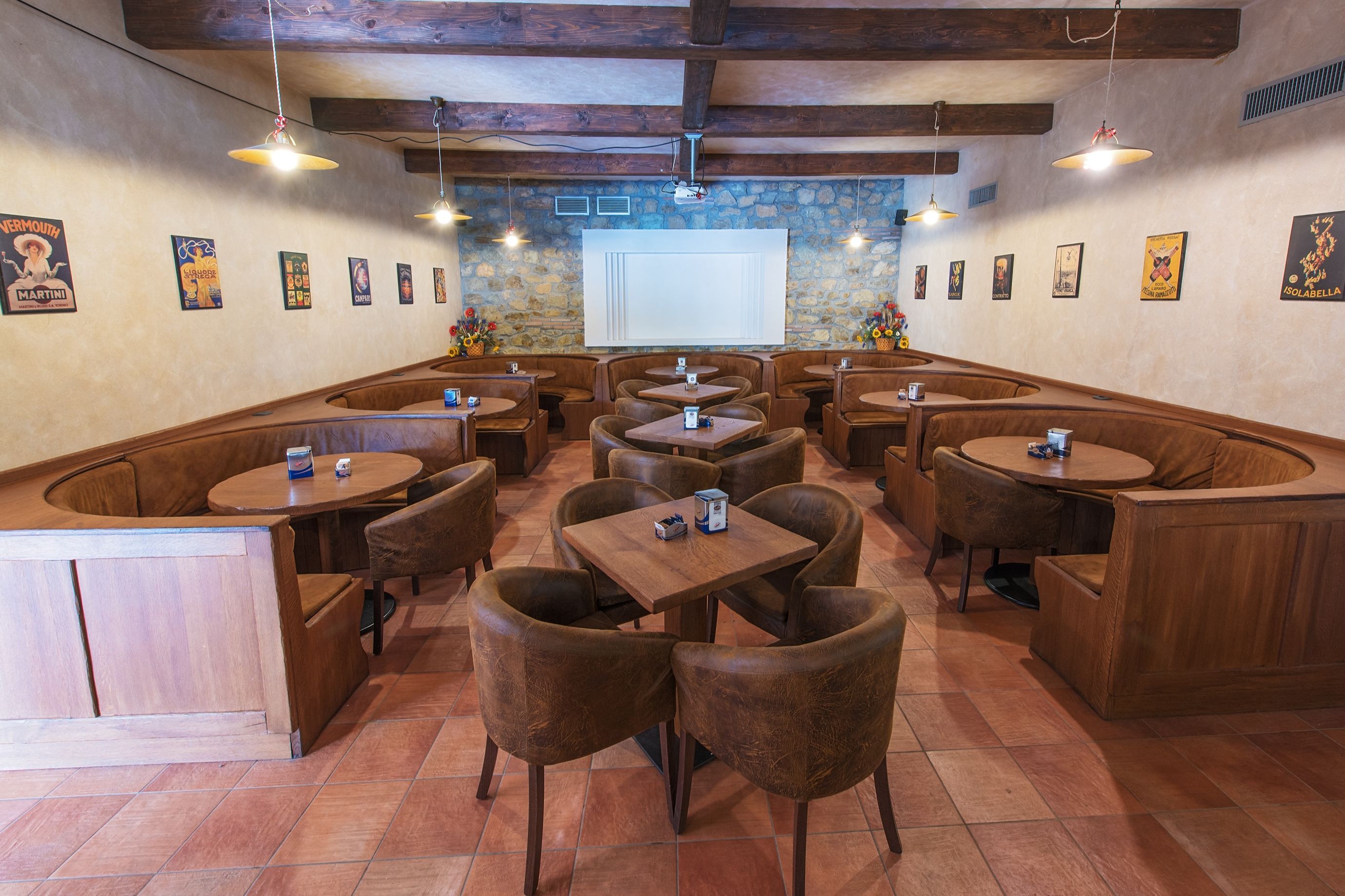 Een restaurant met zitbanken, houten tafels en hangende lampen.