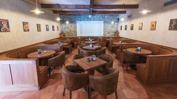 Un restaurant amb seients tipo cabina, taules de fusta i lluminàries penjants.