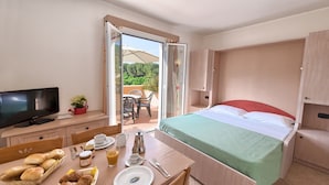 A hotel room with a bed, breakfast setup, and an open door to an outdoor area. - Il Villaggio di Giuele (Finale Ligure)