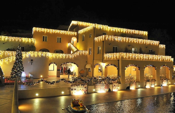A building with multiple levels, decorated with string lights and a Christmas tree. - Il Villaggio di Giuele (Finale Ligure)