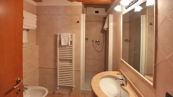 A bathroom with a sink, mirror, shower, and towel rack.