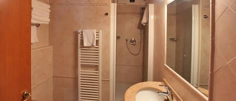 A bathroom with a sink, mirror, shower, and towel rack.