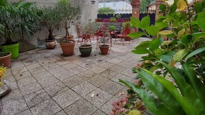 A courtyard with potted plants, a tiled floor, and outdoor furniture. - Belle Occitane (Tarascon-sur-Ariege)