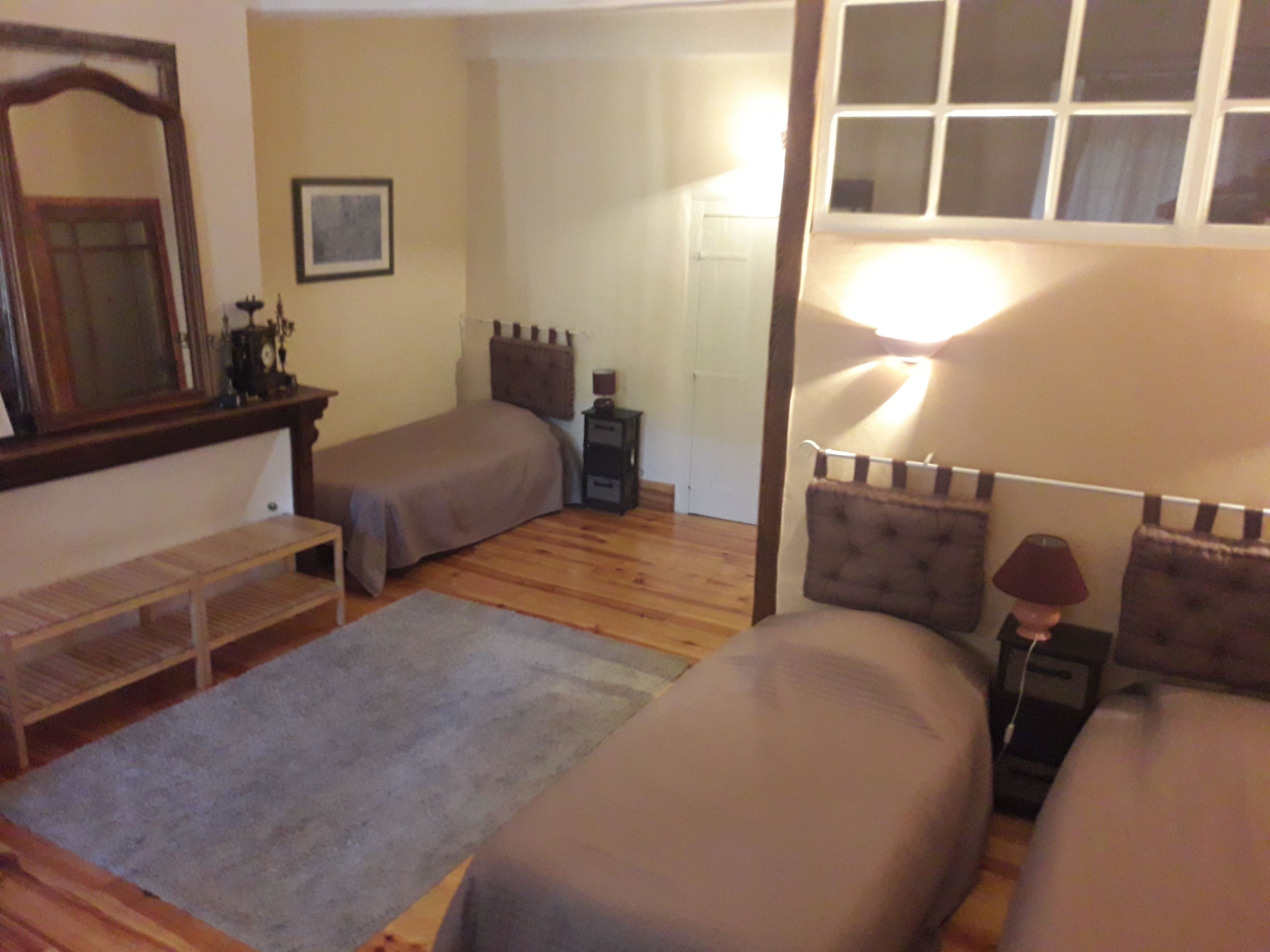 Une petite chambre confortable avec deux lits simples, une table de chevet, une lampe et un miroir.