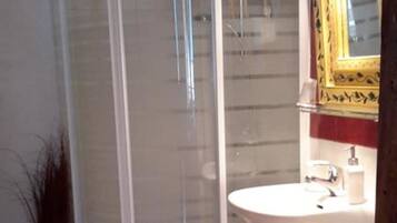 A bathroom with a glass-enclosed shower, a sink with a mirror, and a toilet.