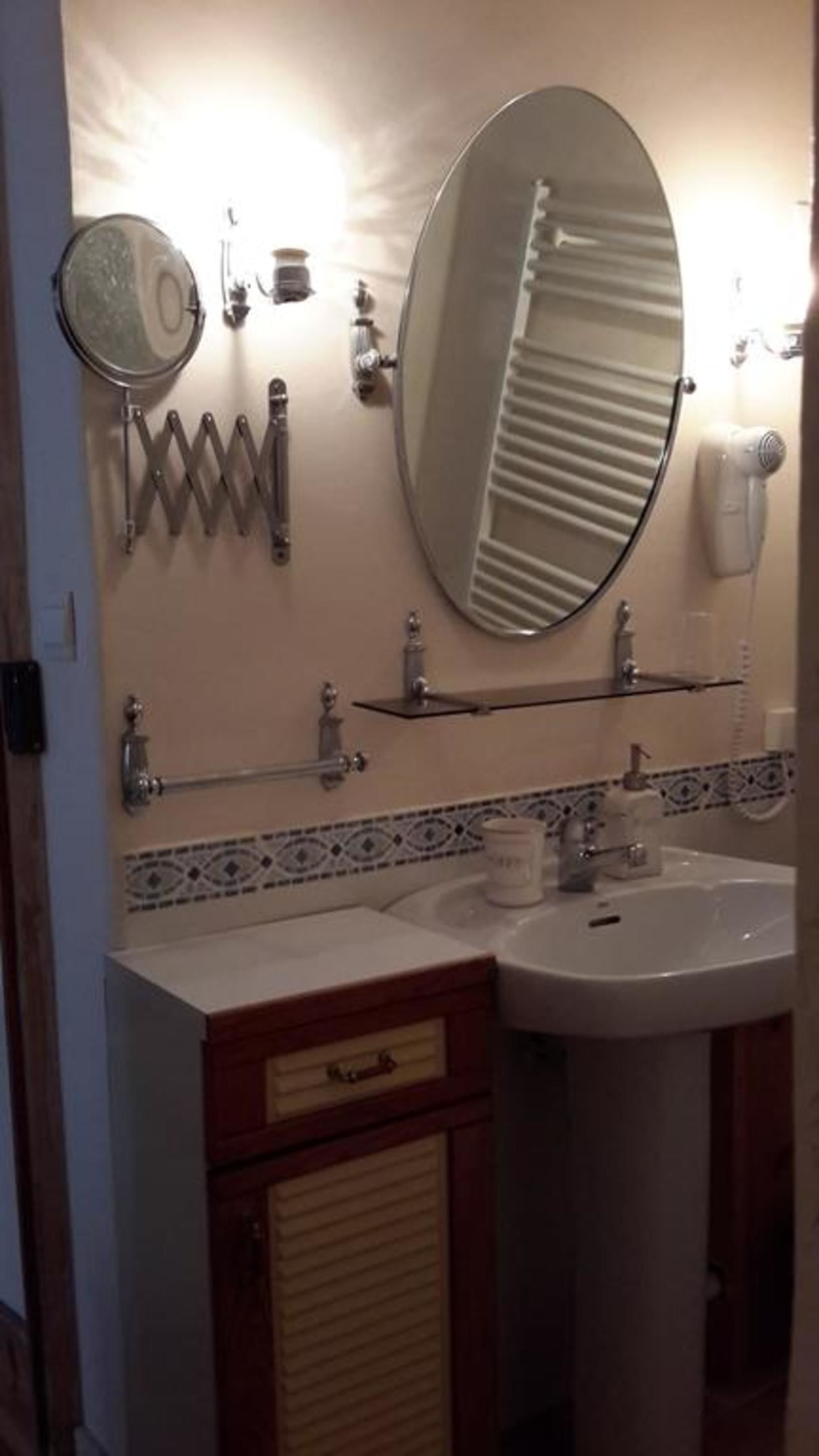 A bathroom with a double sink, a mirror, a towel rack, and a heater.
