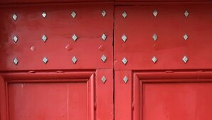 A red door with a metal handle and a keyhole, featuring diamond-shaped studs. - Belle Occitane (Tarascon-sur-Ariege)