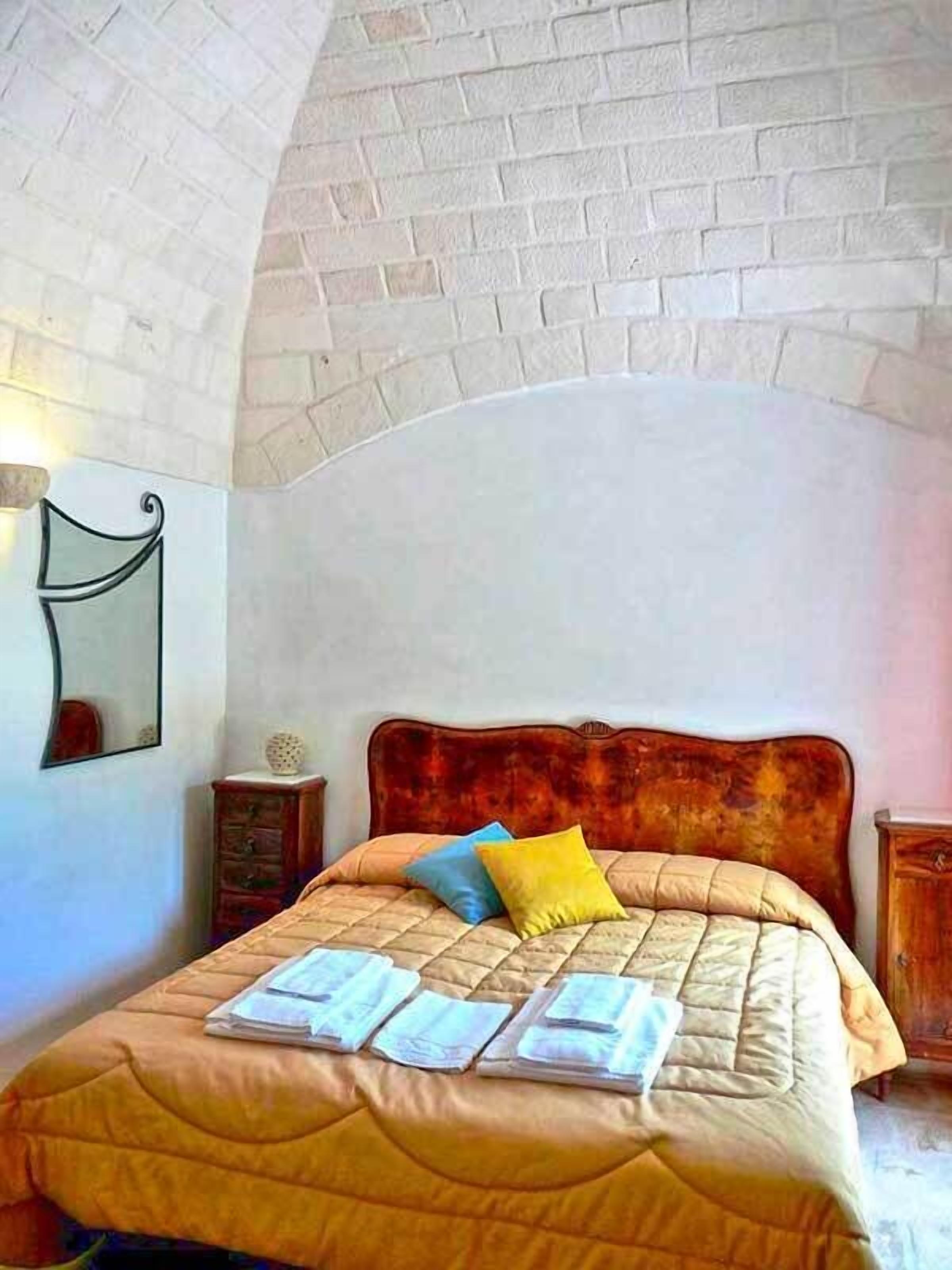 Quarto com teto em padrão de tijolos, cabeceira de madeira e cama com cobertura acolchoada e almofadas.